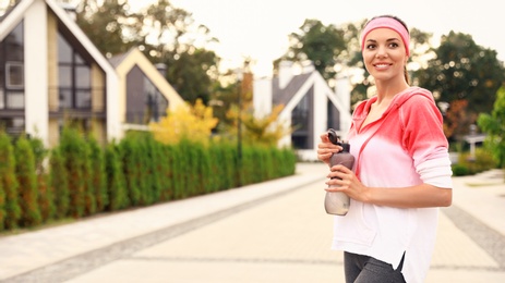 Photo of Beautiful sporty woman drinking water after running on street. Healthy lifestyle