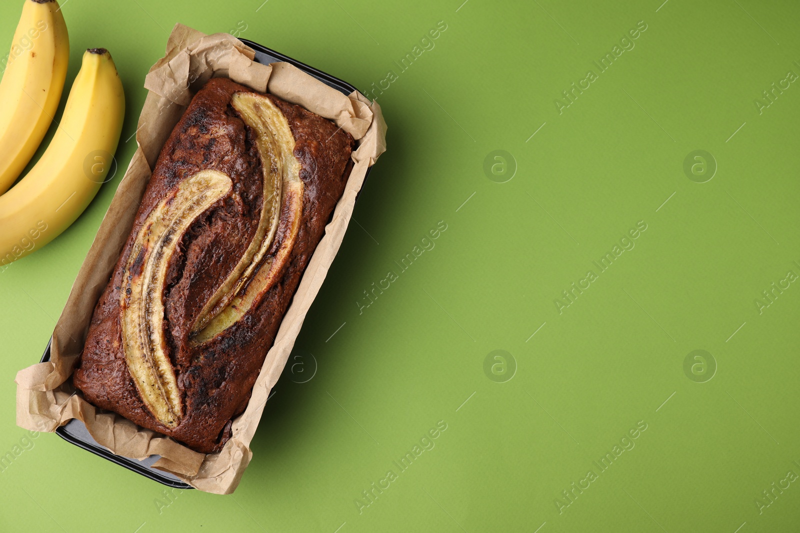 Photo of Delicious banana bread and fresh fruits on green background, top view
