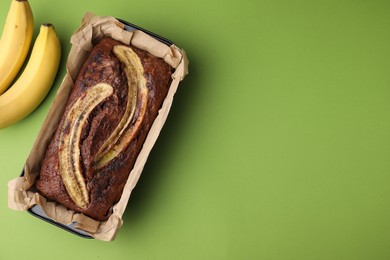 Delicious banana bread and fresh fruits on green background, top view