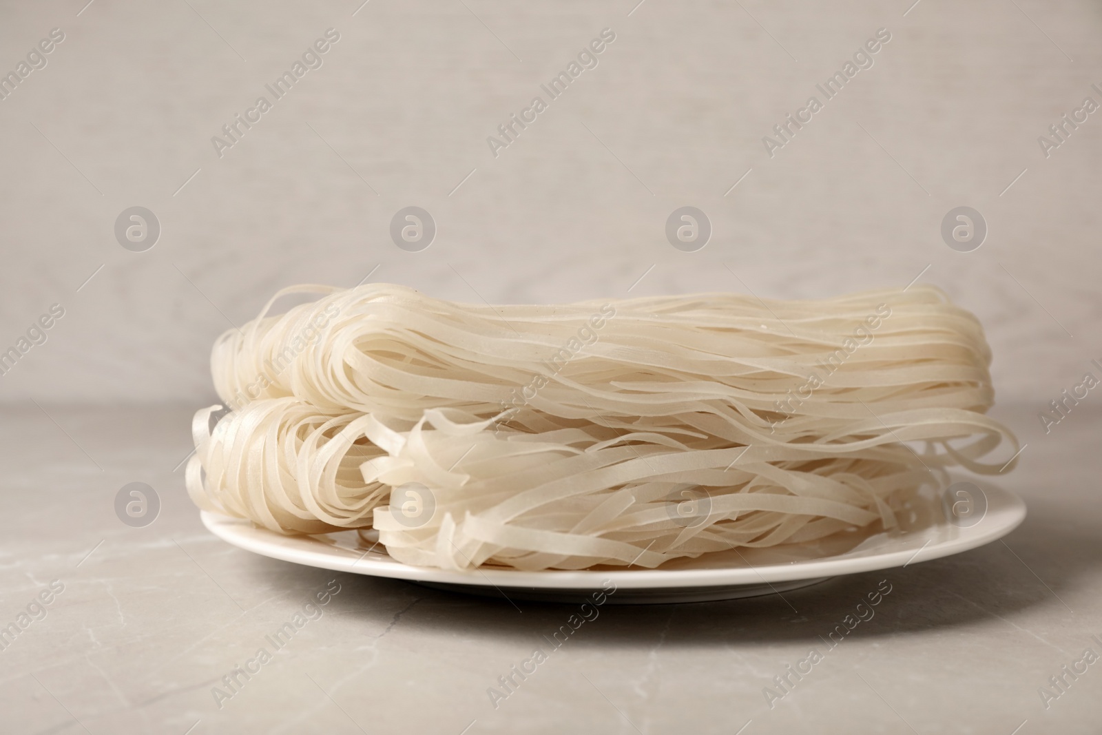 Photo of Plate with raw rice noodles on table. Delicious pasta