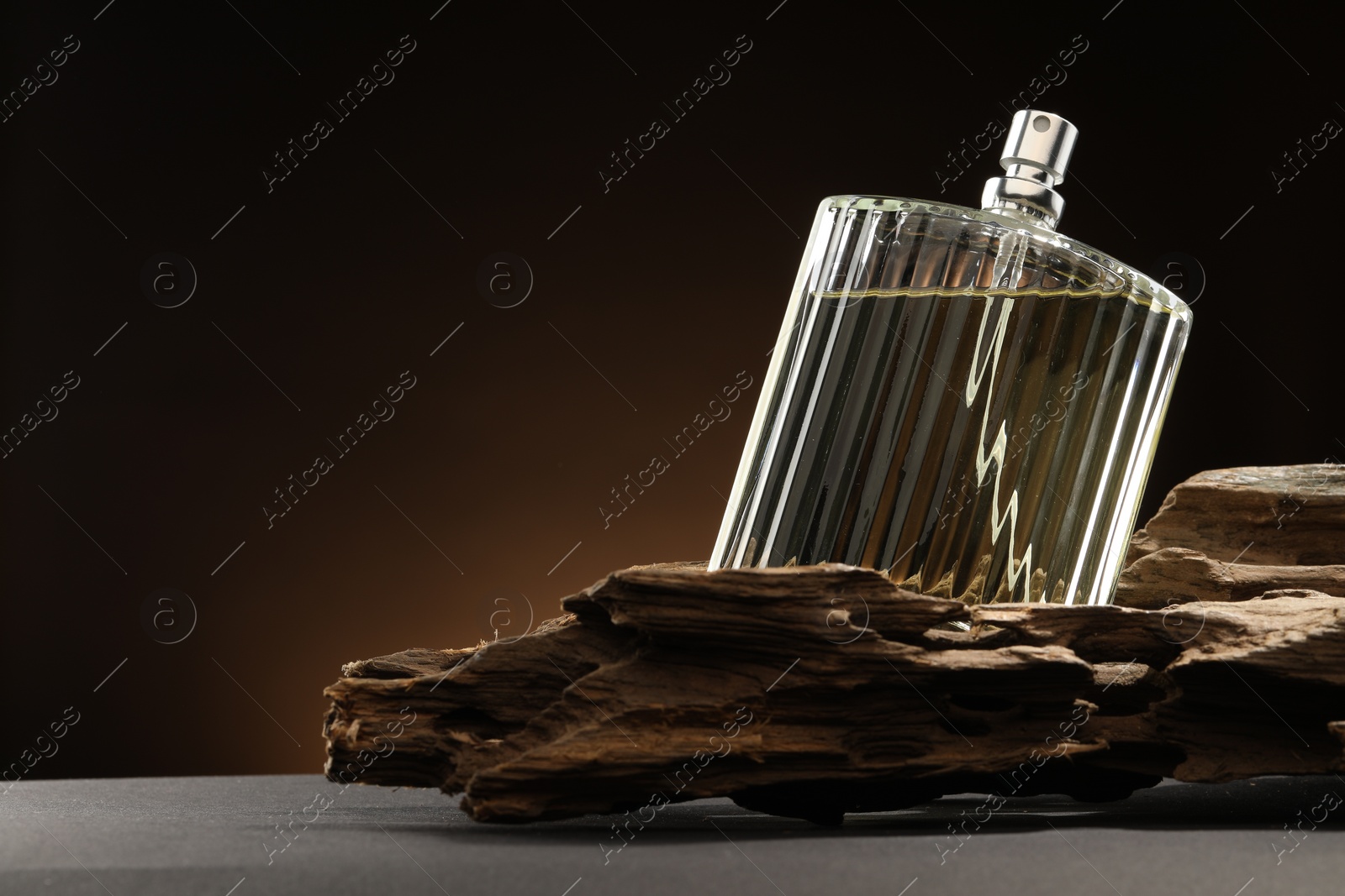 Photo of Luxury men`s perfume in bottle on grey table against dark background, space for text