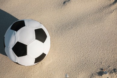 Soccer ball on sand, above view with space for text. Football equipment