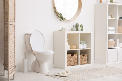 Photo of Modern toilet bowl near white wall in bathroom