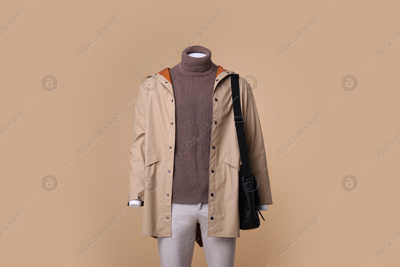 Photo of Male mannequin with bag dressed in stylish coat, turtleneck and pants on beige background