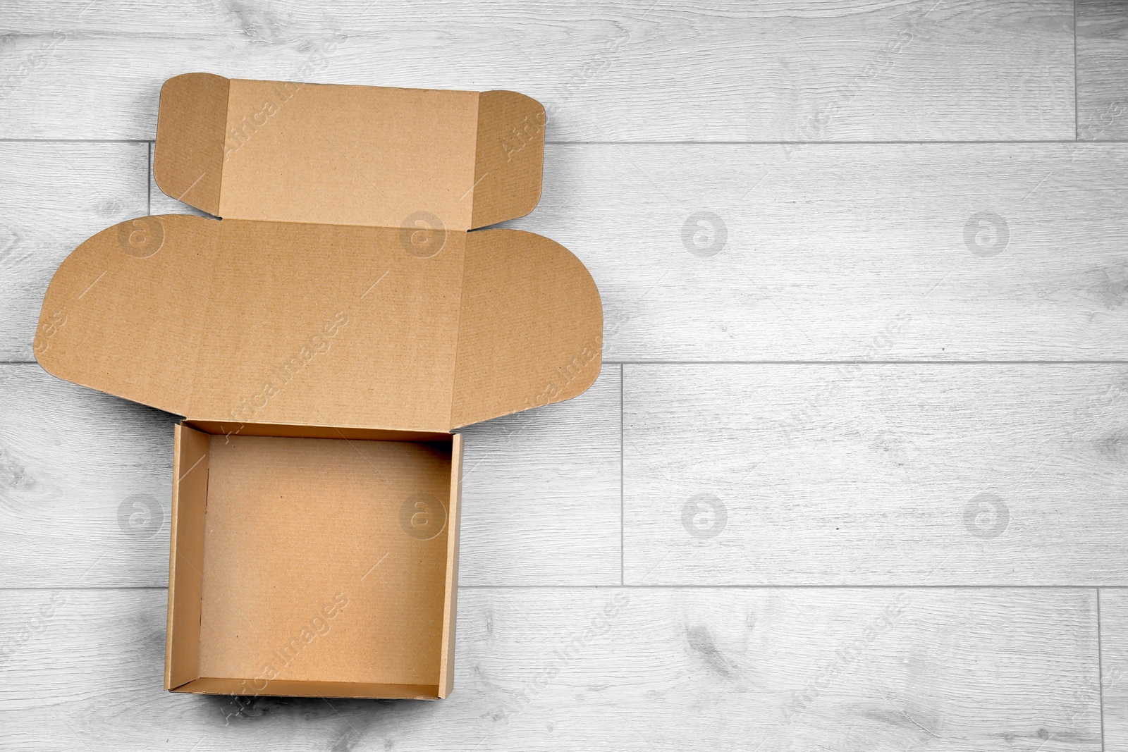 Photo of Open empty cardboard box on wooden floor