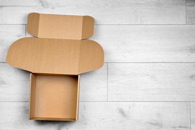 Photo of Open empty cardboard box on wooden floor