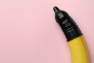 Photo of Banana with condom on pink background, top view and space for text. Safe sex concept