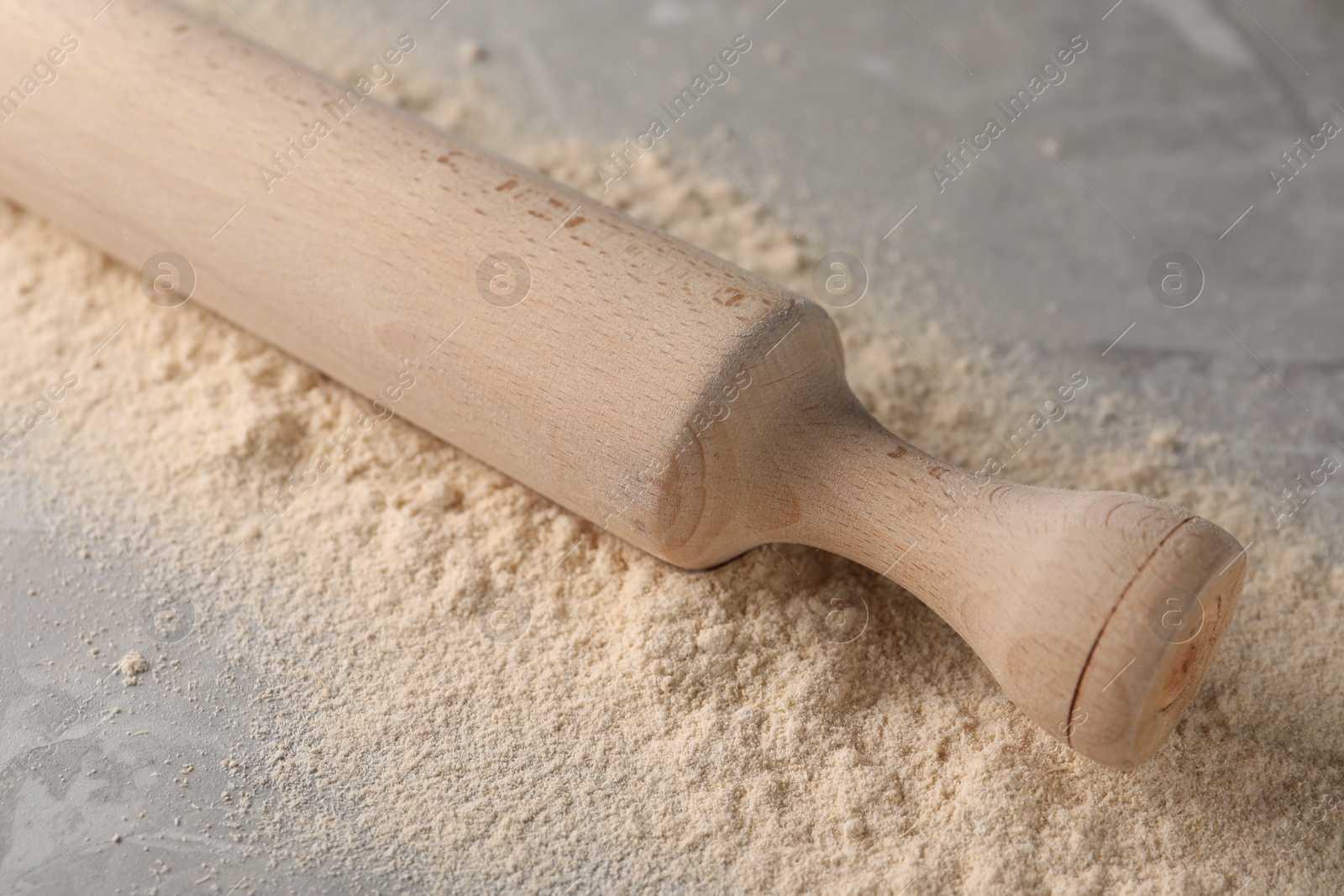 Photo of Flour and rolling pin on grey marble table, closeup