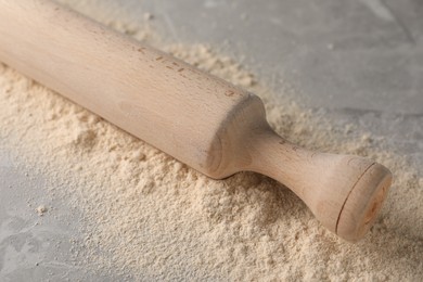 Photo of Flour and rolling pin on grey marble table, closeup