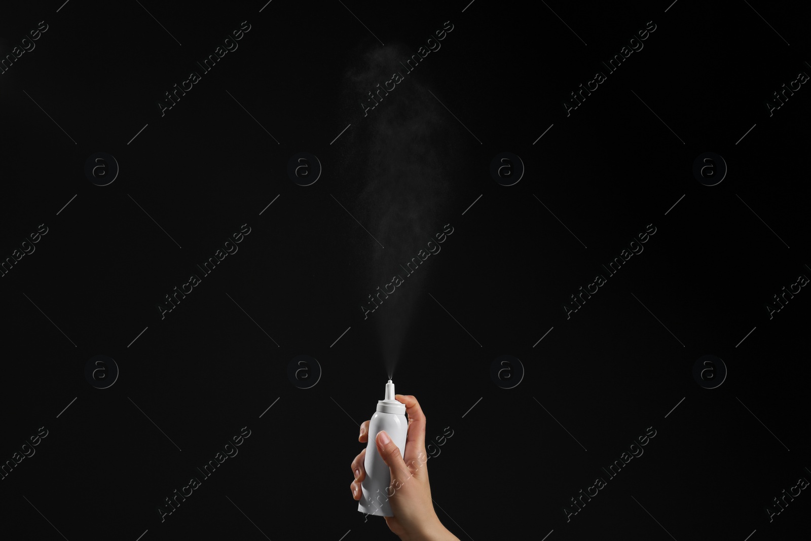 Photo of Nasal congestion. Woman spraying remedy from bottle on black background, closeup