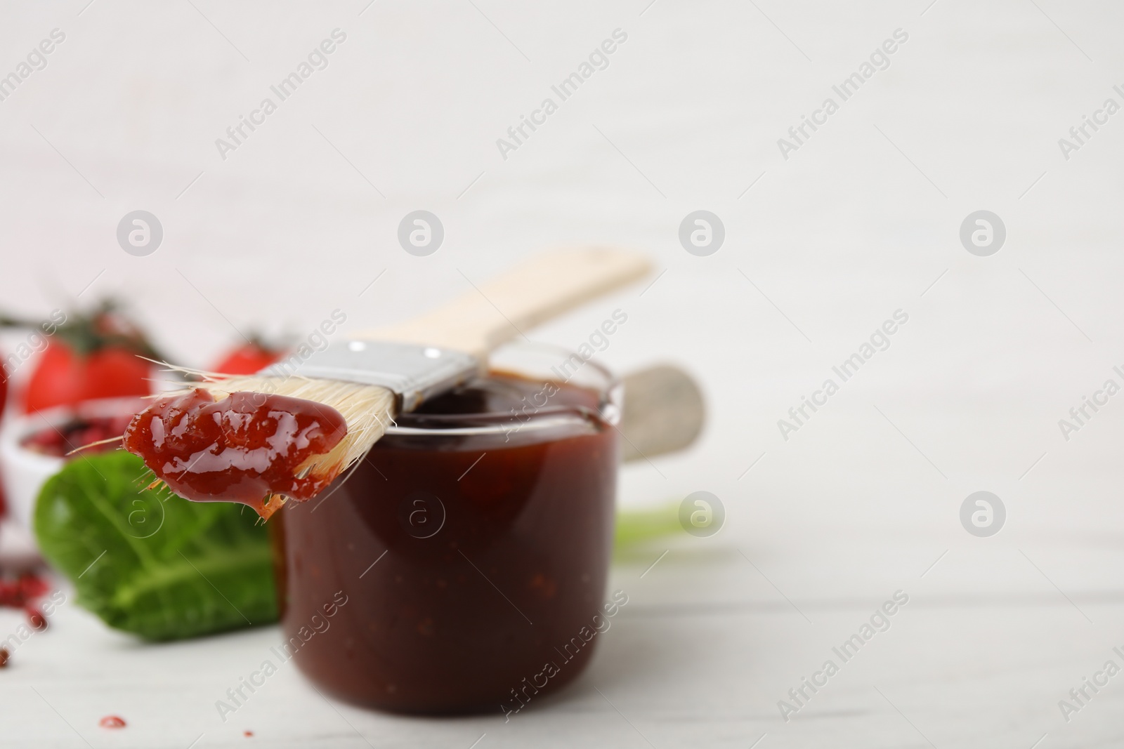 Photo of Marinade and basting brush on white table, closeup. Space for text