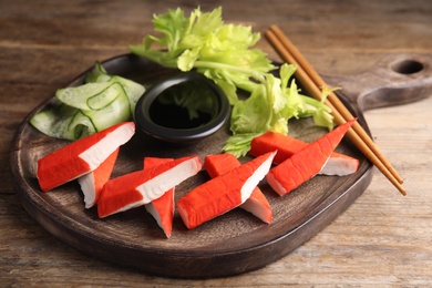 Photo of Fresh crab sticks with lettuce and soy sauce served on wooden table