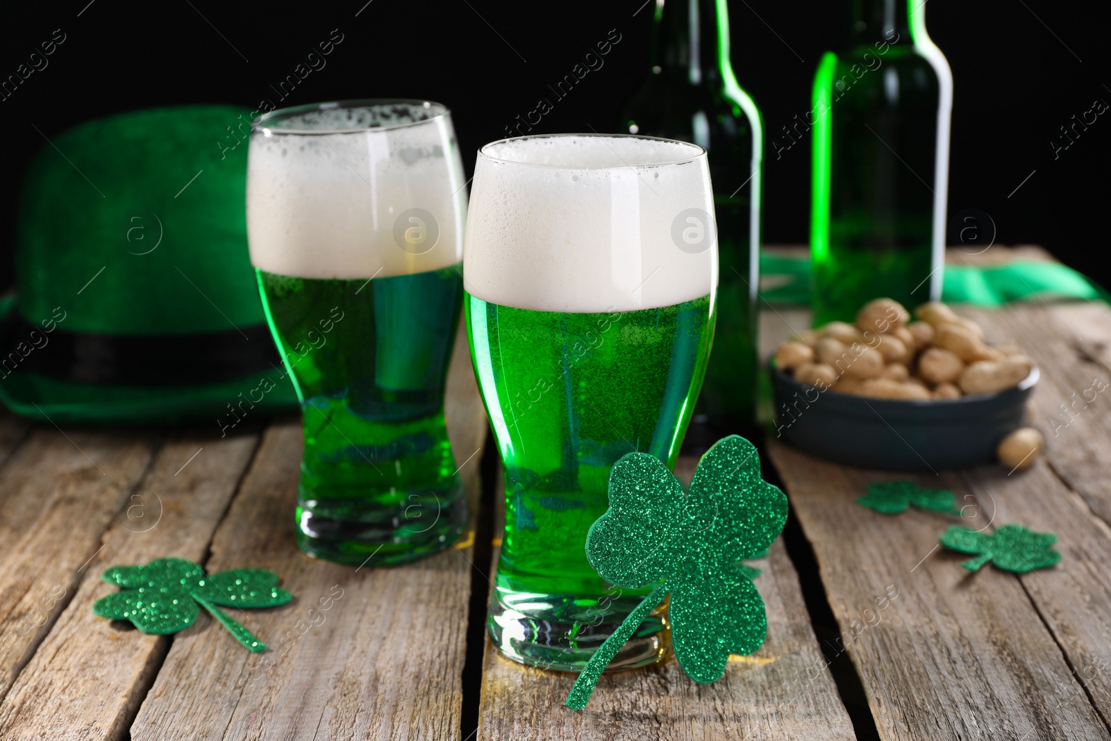 Photo of St. Patrick's day party. Green beer, decorative clover leaves, leprechaun hat and nuts on wooden table