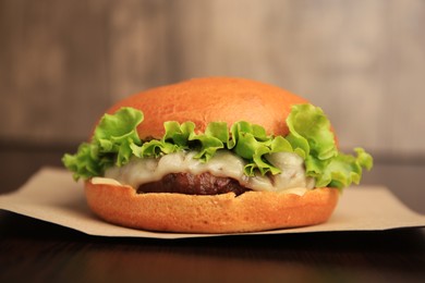 Photo of One tasty cheeseburger on wooden table, closeup