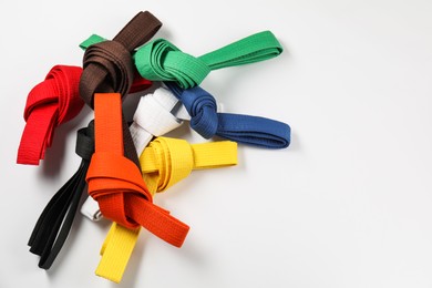 Photo of Colorful karate belts on white background, flat lay. Space for text