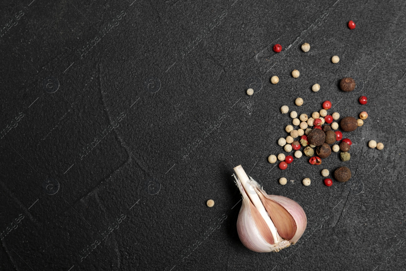 Photo of Flat lay composition with garlic bulb, peppers mix and space for text on table