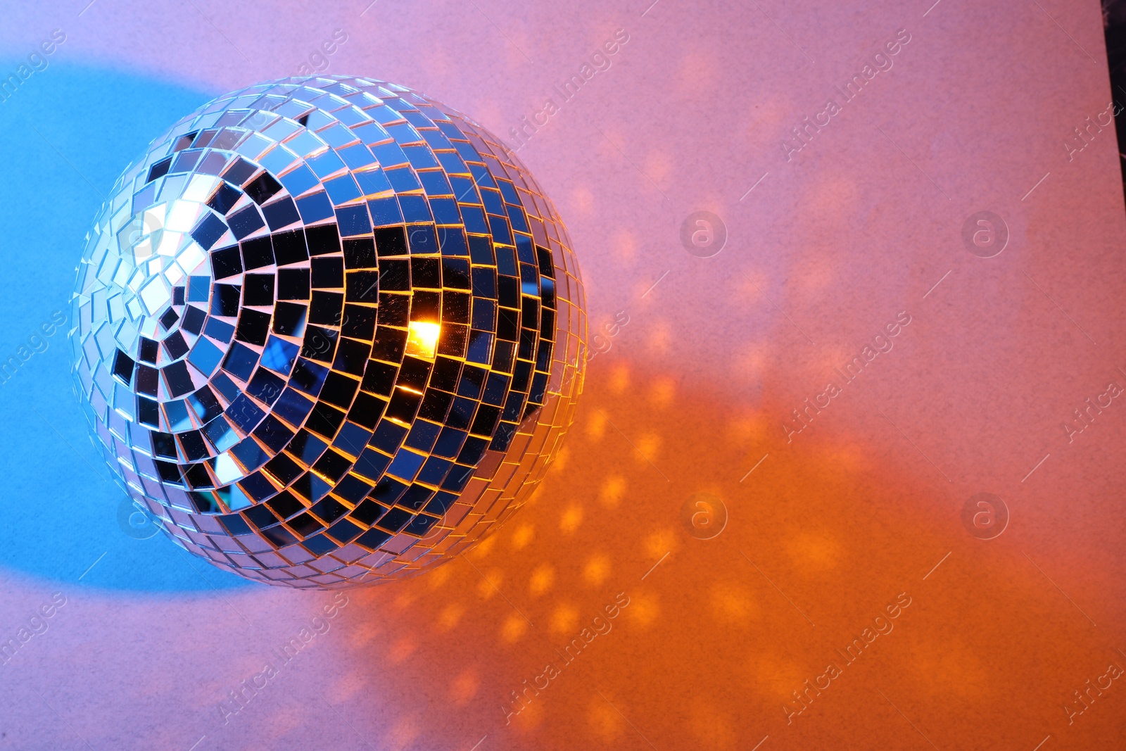 Photo of Bright shiny disco ball on color background. Space for text