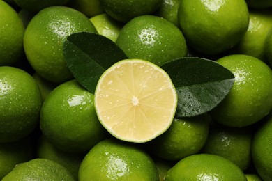 Photo of Fresh limes and leaves with water drops as background, top view