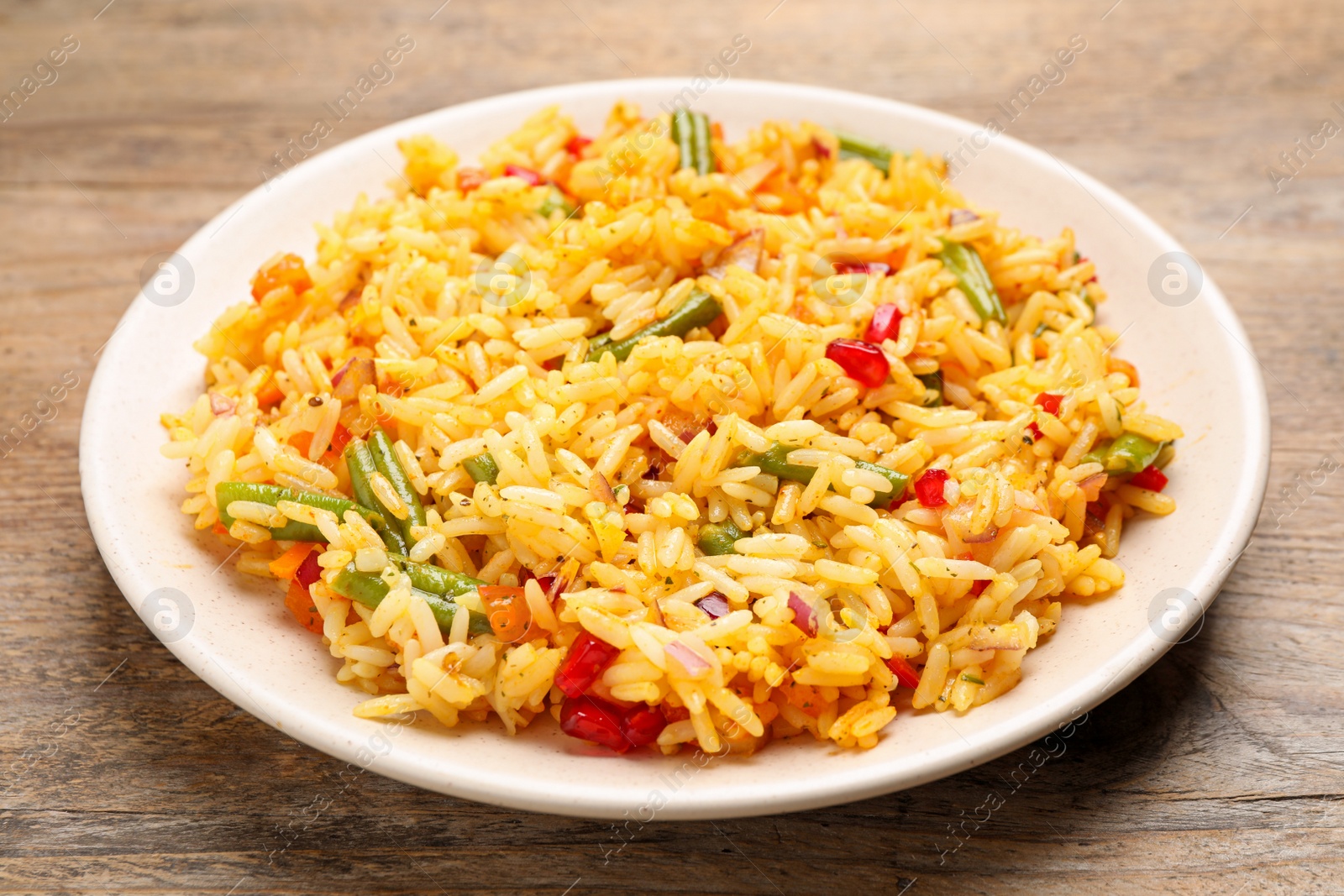 Photo of Tasty rice pilaf with vegetables on wooden table