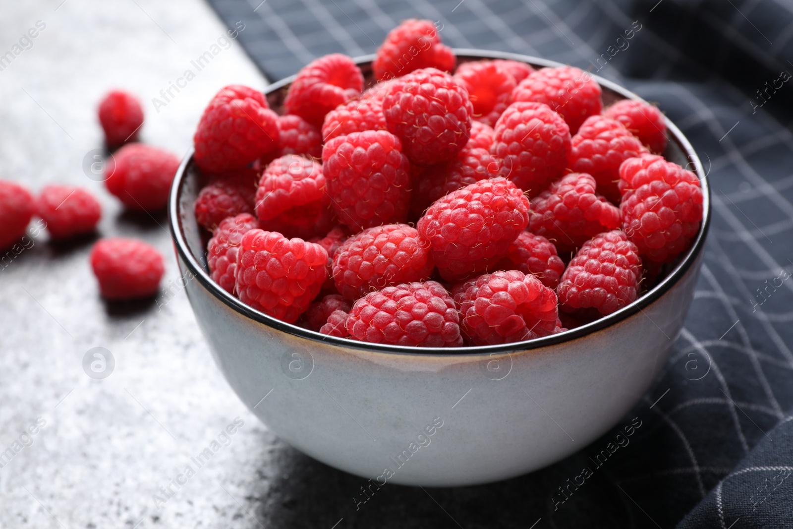 Photo of Delicious fresh ripe raspberries in bowl on grey table, closeup