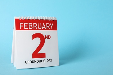 Photo of Calendar with date February 2nd on light blue background, space for text. Groundhog day