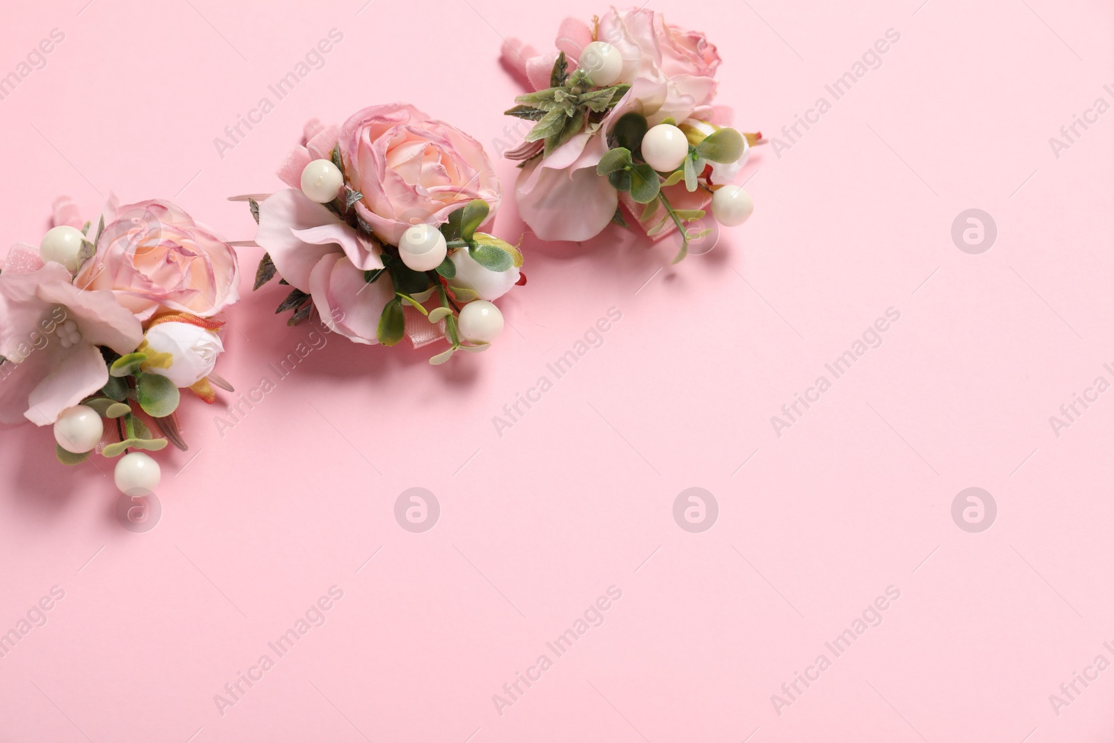 Photo of Stylish boutonnieres on pink background, above view. Space for text