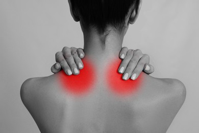 Woman suffering from neck pain on light background, closeup