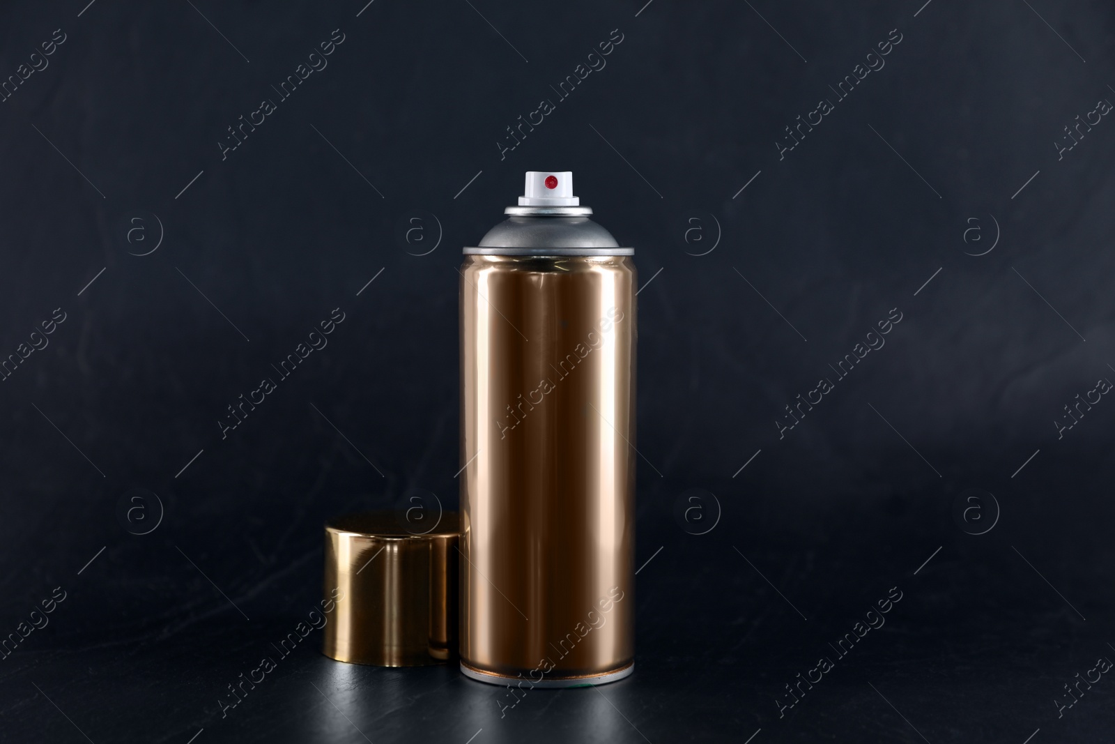 Photo of Golden can of spray paint on black background. Space for text