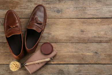 Photo of Flat lay composition with shoe care accessories and footwear on wooden background. Space for text