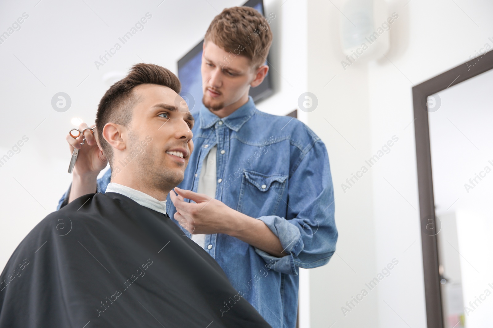 Photo of Professional barber working with client in hairdressing salon. Hipster fashion