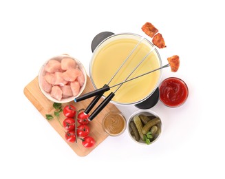 Photo of Fondue pot with oil, forks, meat pieces and other products isolated on white, top view