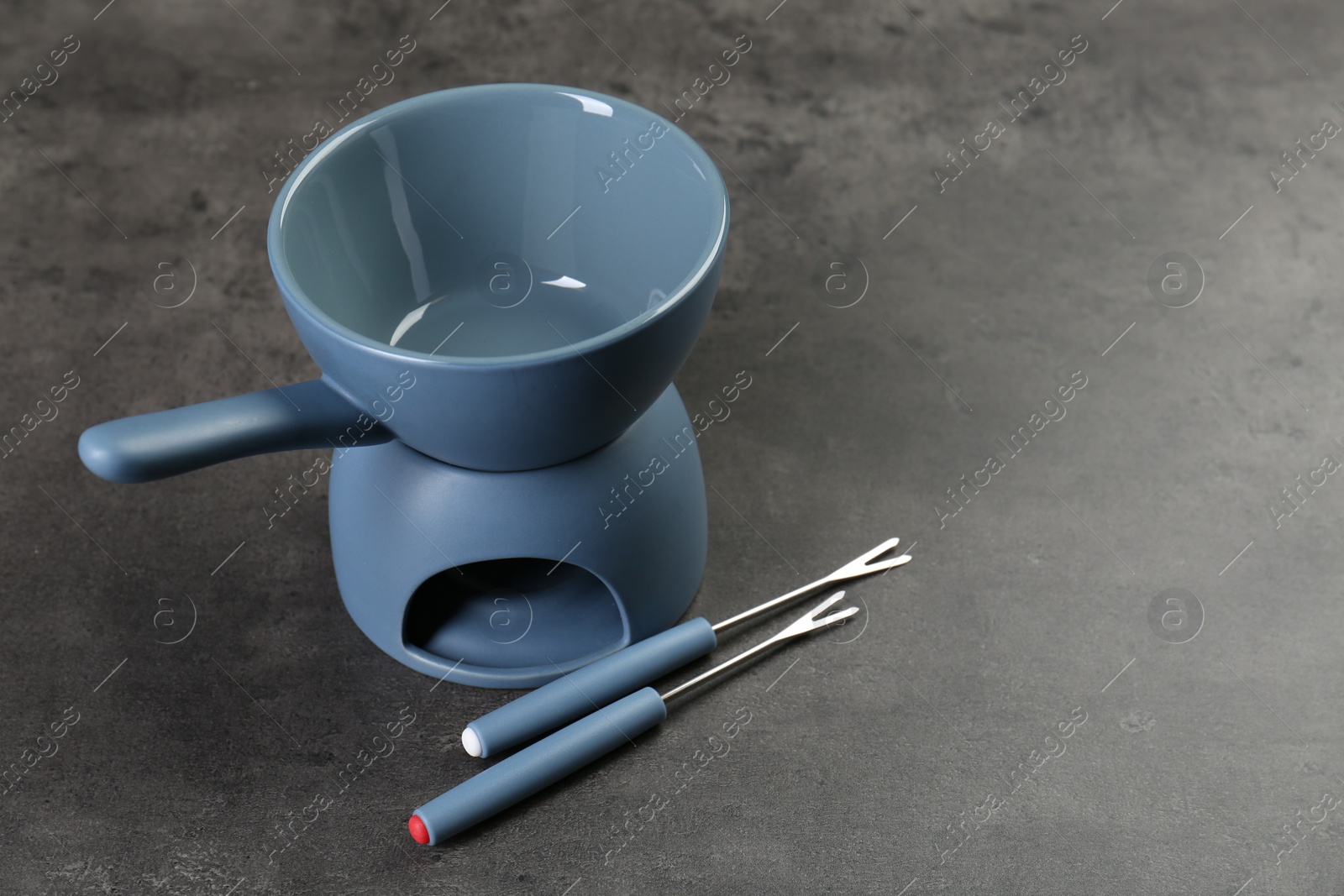 Photo of Fondue set on grey textured table, space for text