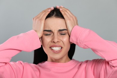 Photo of Woman suffering from migraine on grey background