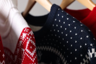 Different Christmas sweaters hanging on rack, closeup