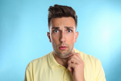 Emotional young man with double chin on blue background