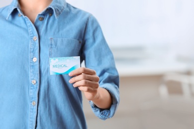 Photo of Woman holding business card indoors, closeup with space for text. Medical service