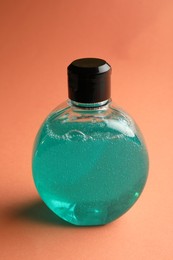 Bottle of blue cosmetic gel on pale orange background