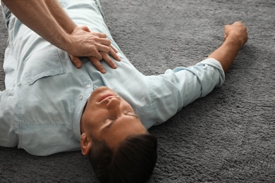 Passerby performing CPR on unconscious man indoors. First aid