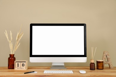 Photo of Modern computer and decor on wooden table near beige wall