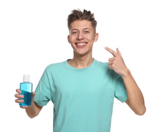 Photo of Young man with mouthwash pointing at his healthy teeth on white background