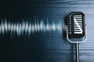 Microphone with radio wave on grey wooden background