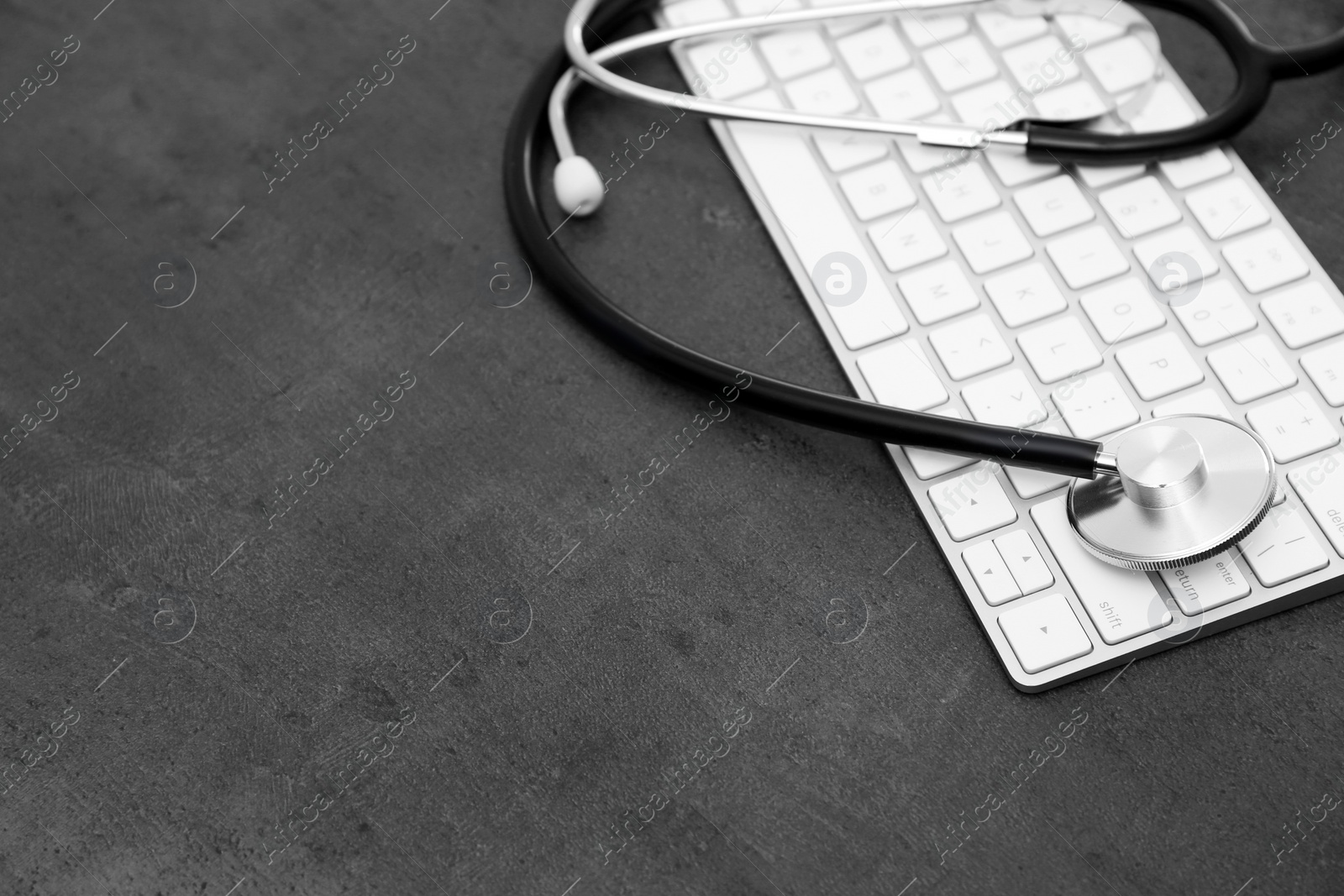 Photo of Modern keyboard and stethoscope on table, space for text. Technical support concept