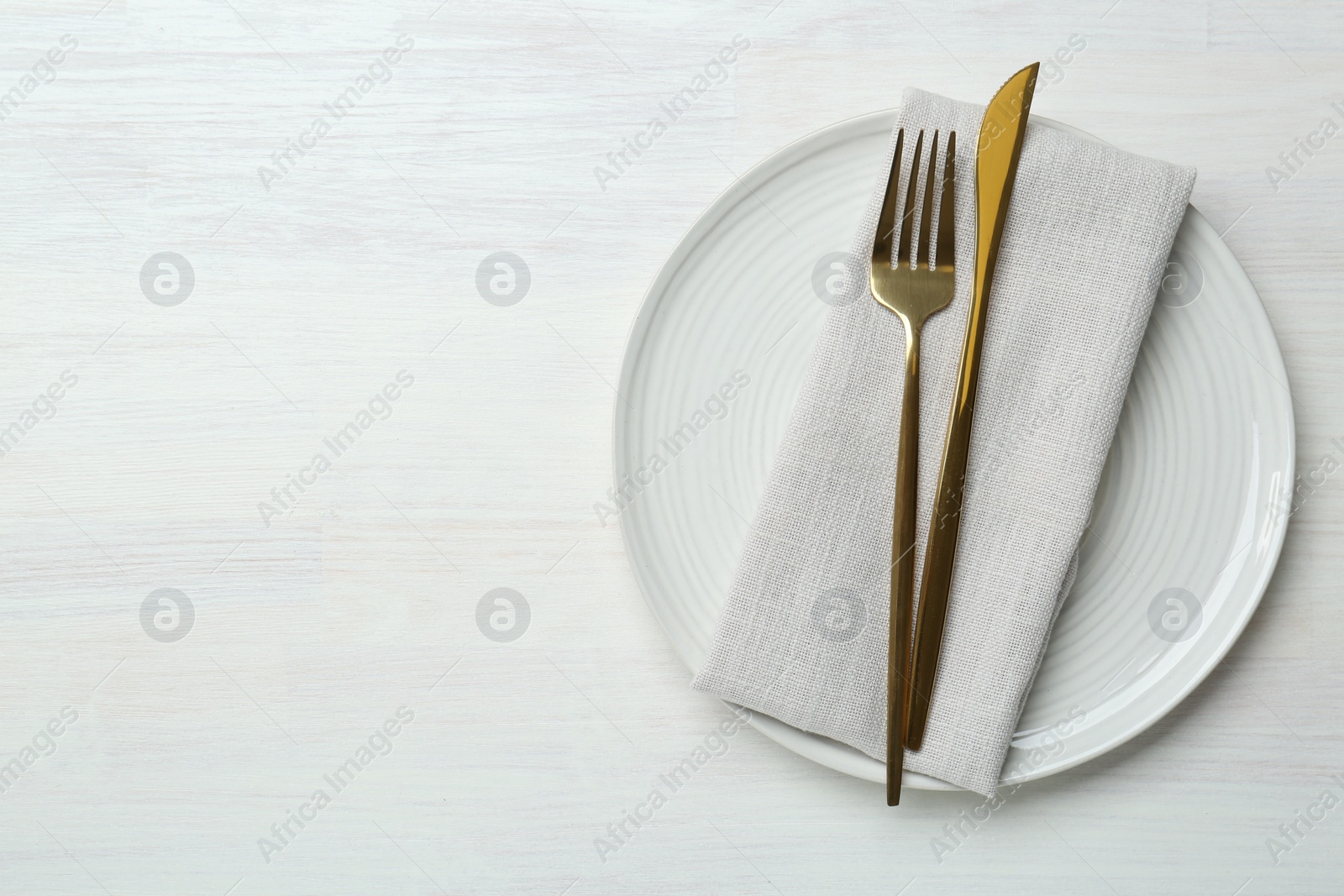 Photo of Stylish ceramic plate, cutlery and napkin on white wooden table, top view. Space for text