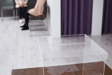 Photo of Ballot box and blurred people on background at polling station