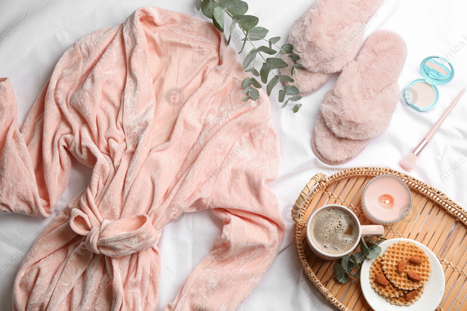 Photo of Flat lay composition with fluffy slippers and bath robe on white bedsheet. Comfortable home outfit