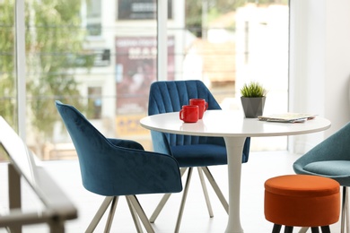 Photo of Stylish room interior with round table and comfortable chairs