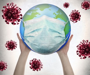 Man holding Earth with medical mask on white background, closeup. Concept of coronavirus outbreak