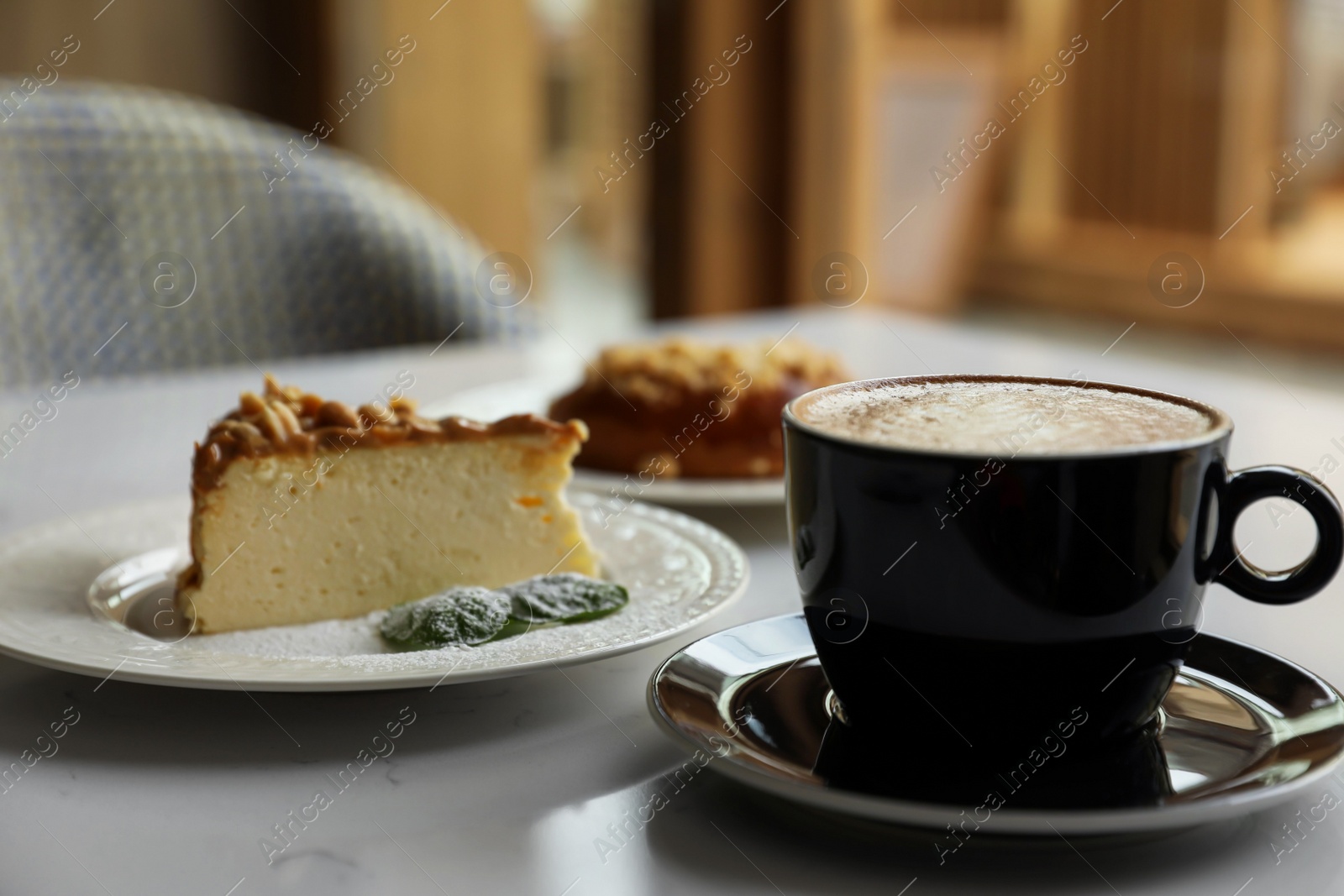 Photo of Cup of fresh coffee and desserts on table indoors