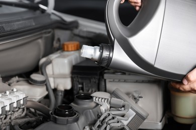 Photo of Man pouring motor oil into car engine, closeup