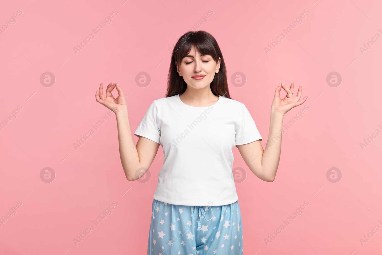 Photo of Woman in pyjama meditating on pink background